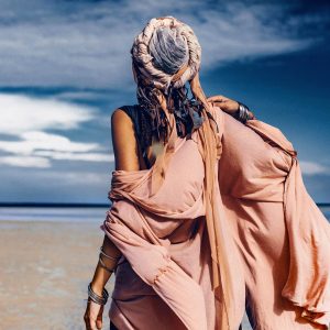 young stylish woman with fashionable boho accessories on the beach windy time